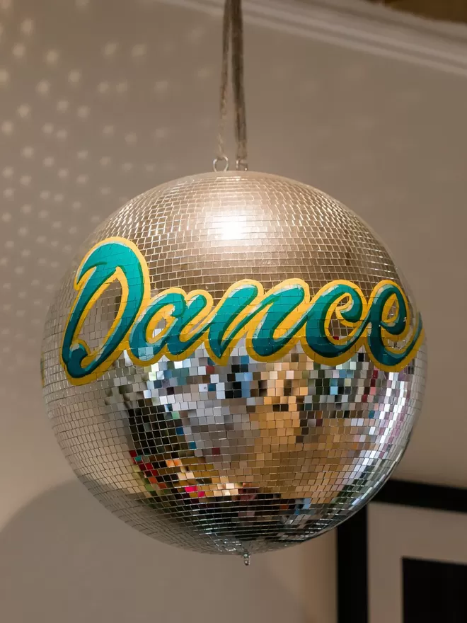 Close up of the blue and yellow lettering on a disco ball saying 'dance'