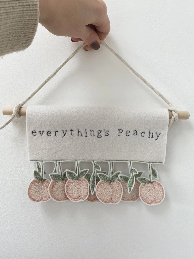 Hand holding everything's peachy banner against wall.