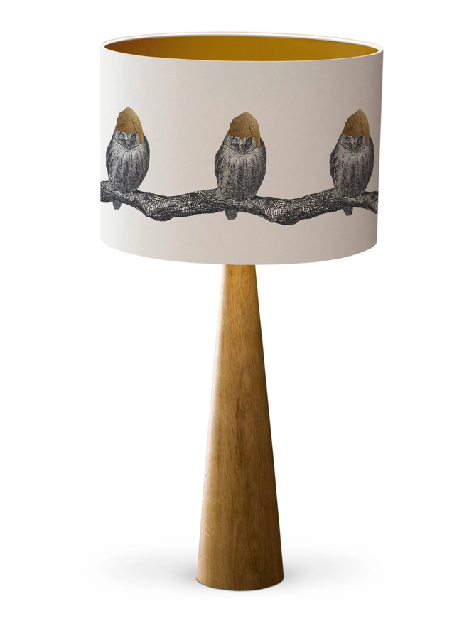 Drum Lampshade featuring little owls wearing a gold nightcap sitting on a branch with a gold inner on a wooden base on a white background