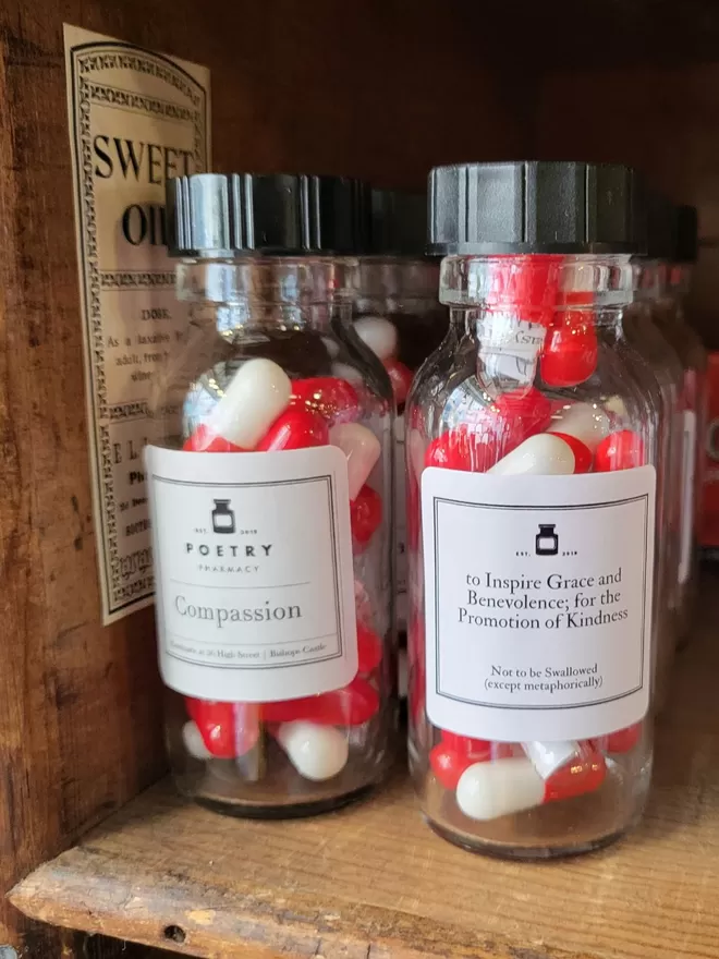 Glass bottles of red and white compassion poetry pills on a shelf at the Poetry Pharmacy