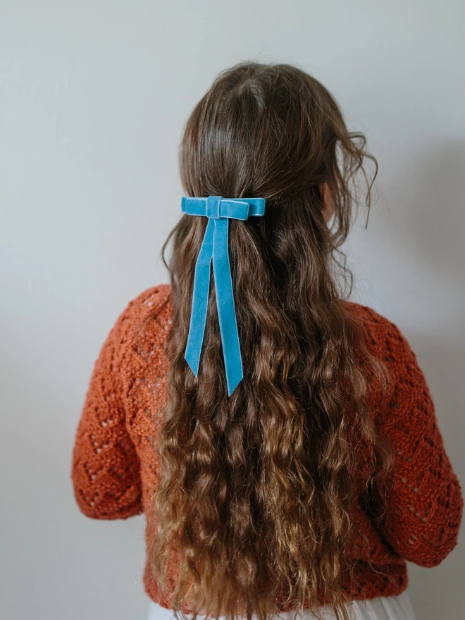 Girl with long brown hair and blue velvet hair bow