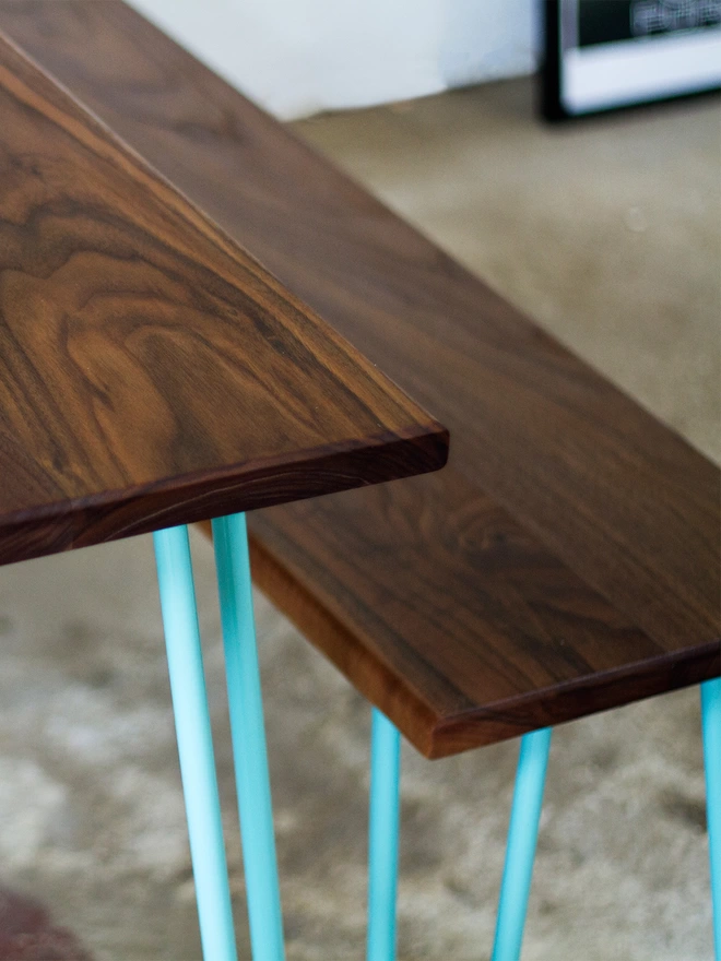 corner angle view of a hairpin leg dining set with walnut table and bench tops and turquoise hairpin legs