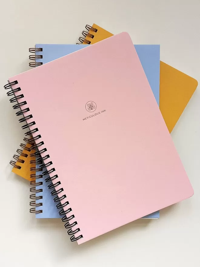 Meticulous Ink Spiral notebooks in blue, pink and orange.