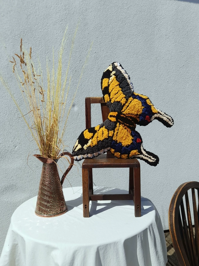 Yellow Swallow Tail Cushion on table in kids vintage chair still life