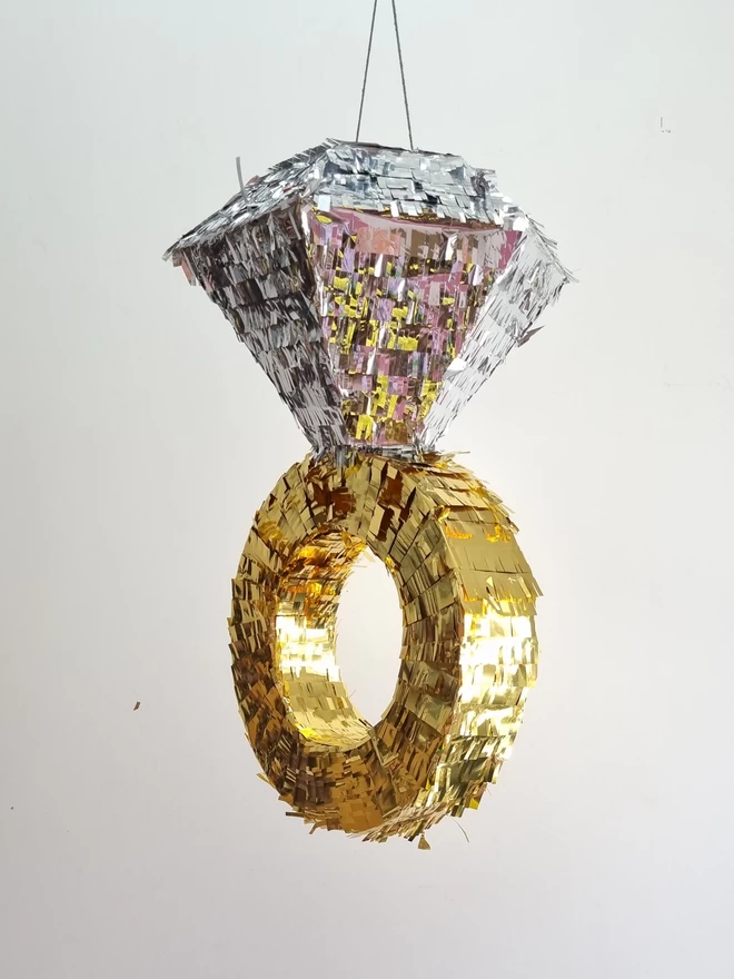 Diamond ring shaped pinata in gold and silver on a white background