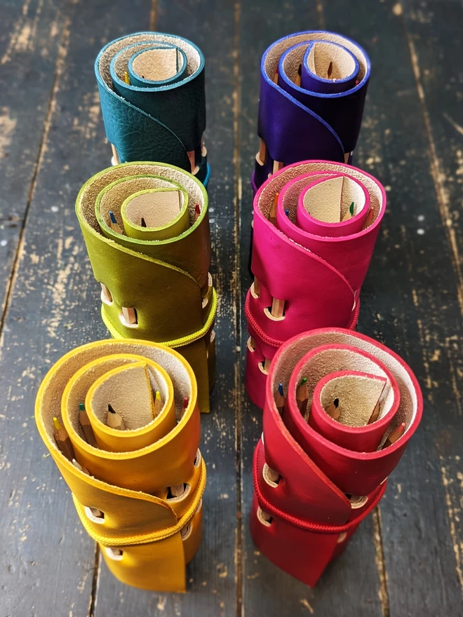 Rolled leather pencil rolls, viewed at a 45 degree angle to show top and sides.