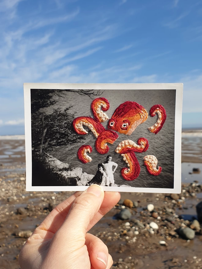 B&W photo of couple with embroidered octopus behind them, held against beach background 