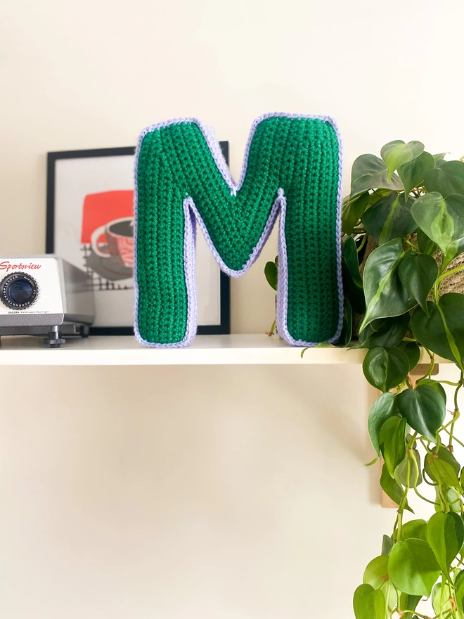 Cushion shaped like the letter M in Grass Green and Lilac