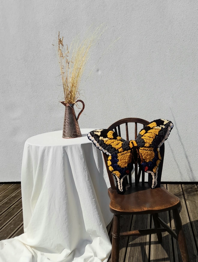 Large Yellow Swallow Tail Butterfly standing up on wooden chair by table