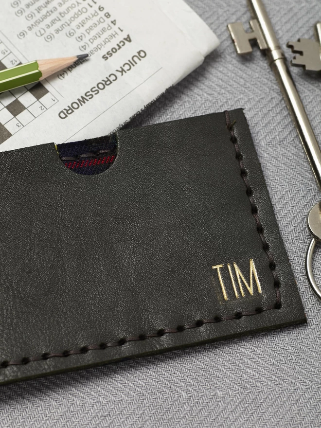 Green leather card holder with tall simple lettering.