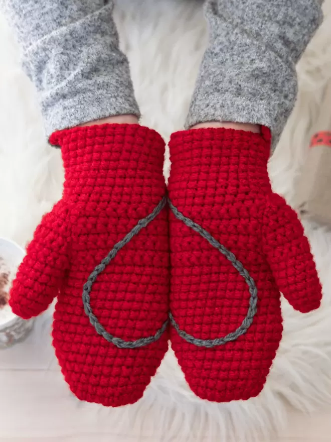 red crocheted mittens with grey heart embroidery