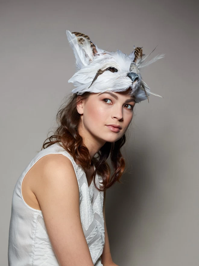 Woman wearing luxury white fox party mask atop her head as a headdress