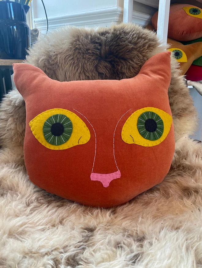 ginger cat cushion on a sheepskin rug