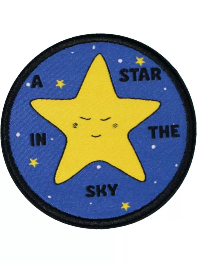 A blue circular patch with a large yellow star, smiling in the centre. In the surrounding night sky are small stars and text saying 'a star in the sky.'
