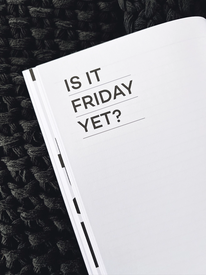 Close up of a quote in the notebook reading "Is it Friday Yet?"
