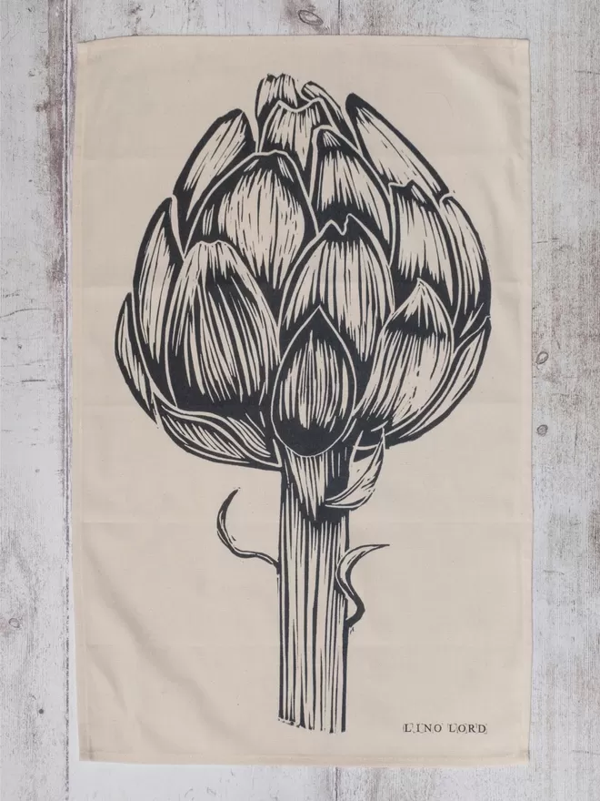 Picture of a tea towel with an image of an artichoke, taken from an original lino print