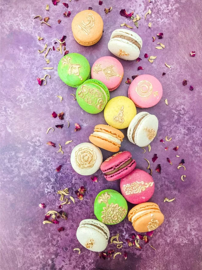 colourful macarons with gold mehndi henna designs painted on against purple background