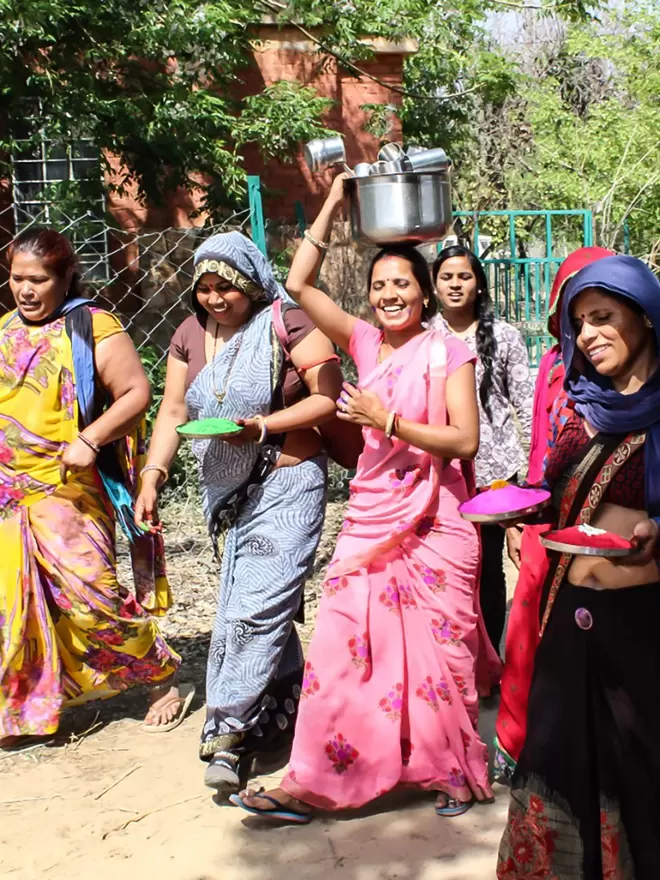 Group of women wearing brightly coloured saris looking happy