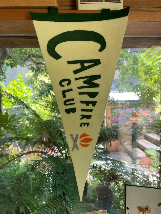 Campfire Club Pennant flag hanging in front of a window.