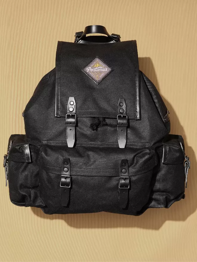 Absolute Back Rockness backpack with black hardware and black leather trim, shown on plain taupe background.