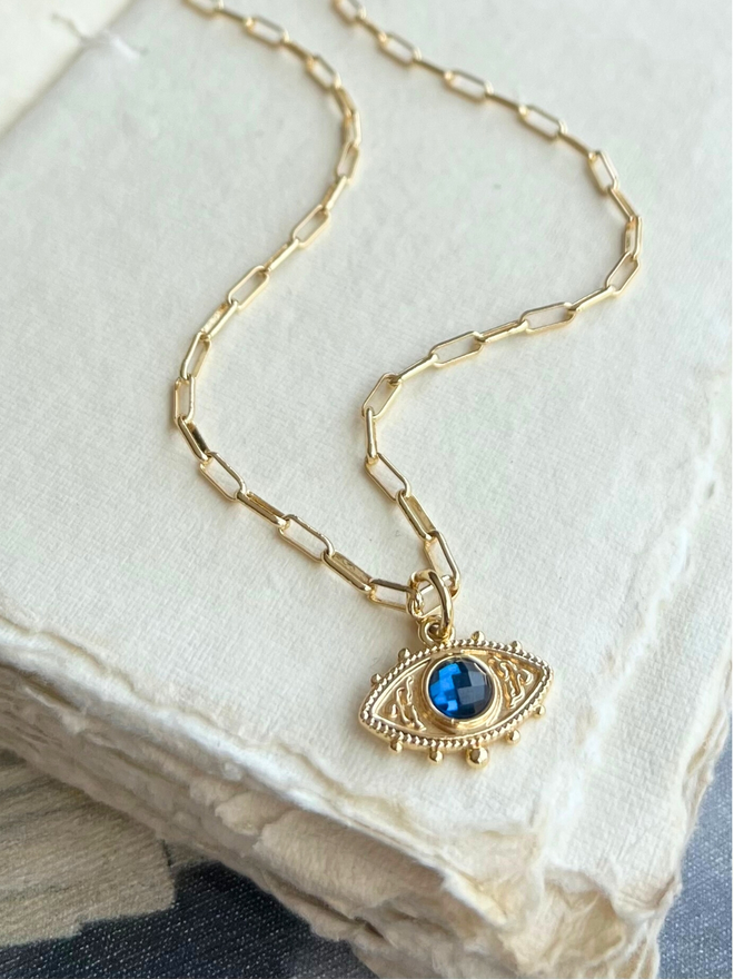 Blue and gold evil eye necklace on gold paperclip style chain