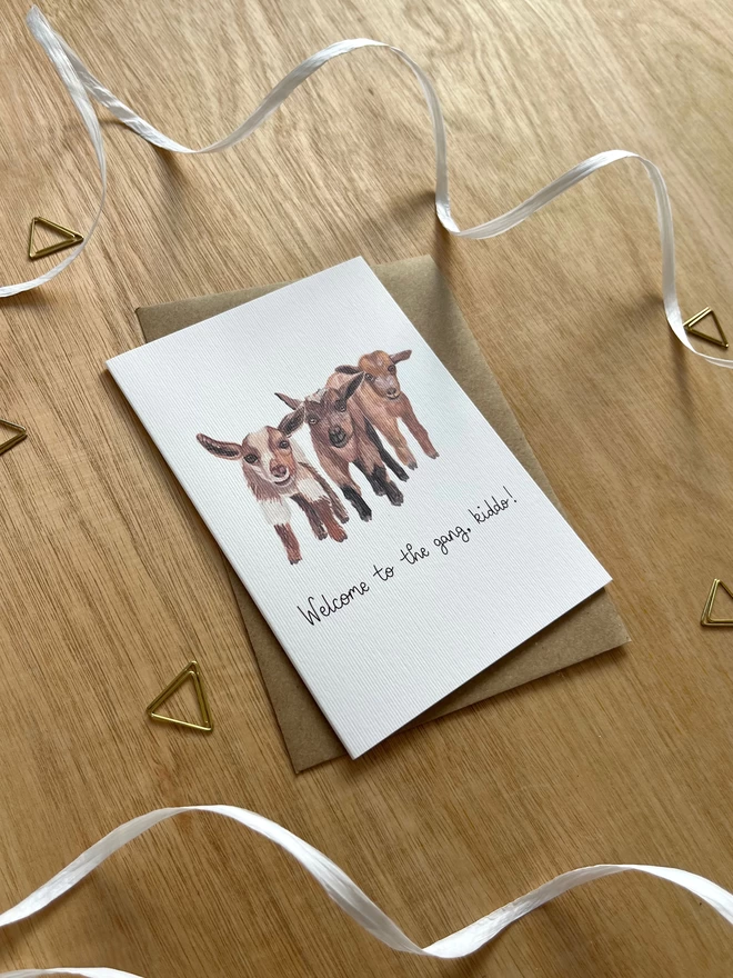 a greetings card featuring three baby goats with the phrase “welcome to the gang kiddo”