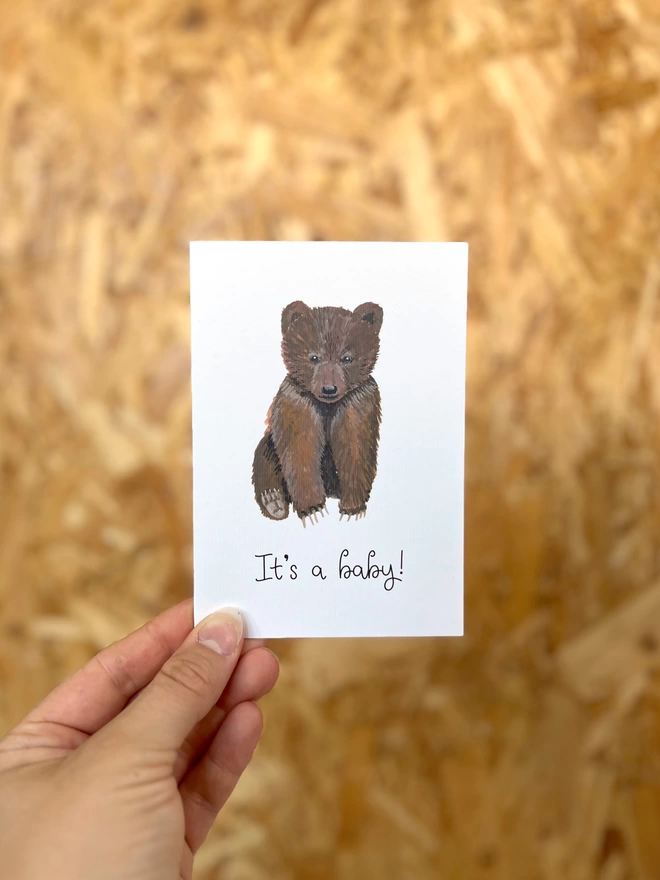 a simple greetings card featuring a baby brown bear cub with the phrase “It’s a baby!”