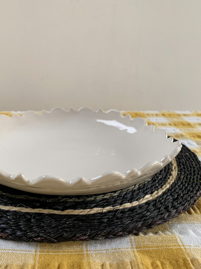 side view of a white fiore edge serving bowl on a placemat