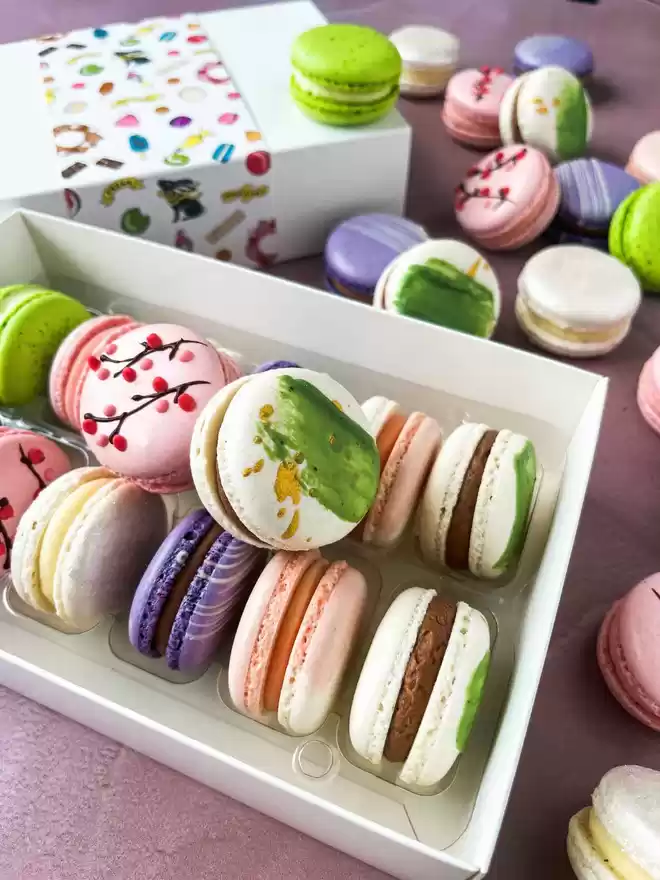 an assortment of colourful spring themed macarons in a white gift box