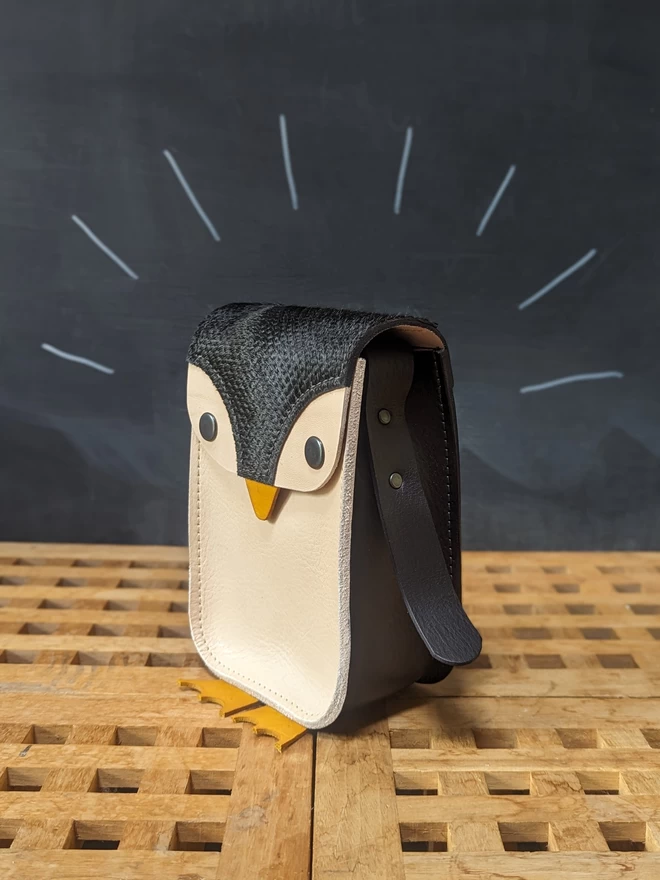 Front and side view of handmade leather penguin cross- body bag.