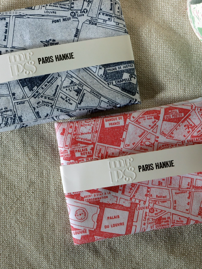 two folded Mr.PS Paris Hankies, one in midnight blue and one in coral 