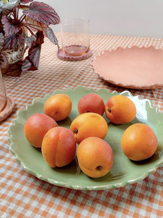tabletop scene of sage green fiore edge serving bowl with apricots in 