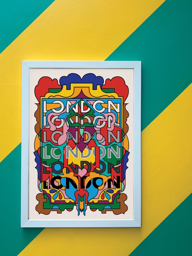 A vibrant, portrait print containing all the colours of the London Underground lines, with the word London repeated six times from top to bottom. The picture is hanging in a white portrait frame against a wall painted with thick diagonal green and yellow stripes.