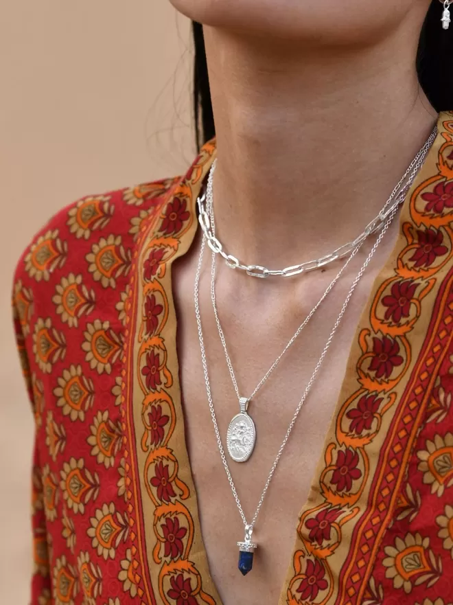 Model wearing red kimono with long silver lapis pendant and silver oval coin pendant with shorter silver hammered chain