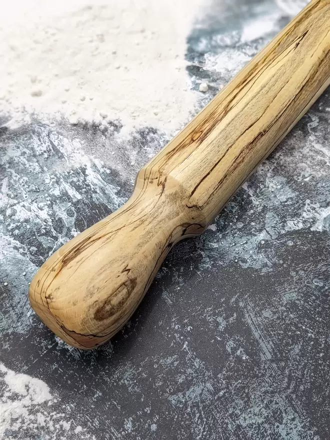 A close up of a stunning hand made rolling pin in Spalted Beech by Something From The Turnery. Displaying the all-natural detailing on the left hand side of the rolling pin. 