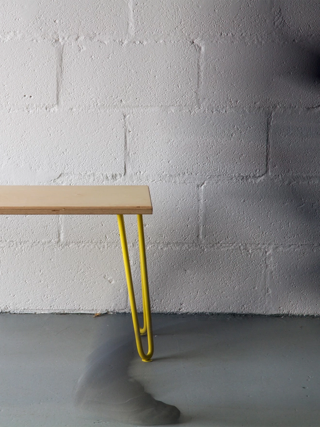 end of a hairpin leg bench with oak top and yellow legs