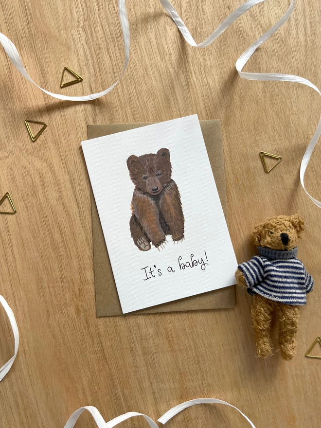 a simple greetings card featuring a baby brown bear cub with the phrase “It’s a baby!”