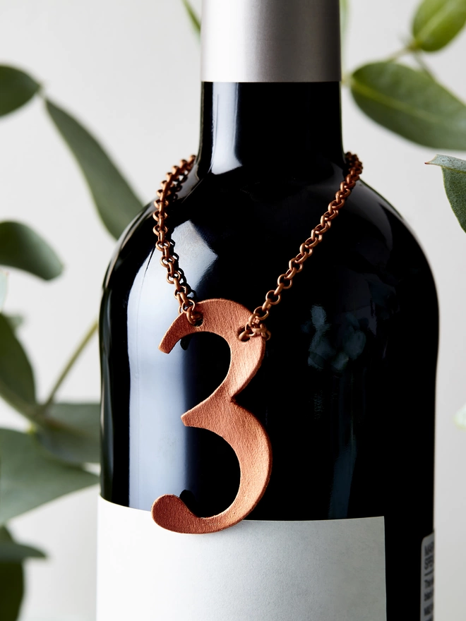 Copper leather number 3 set on a bottle of red wine. Perfect anniversary gift.