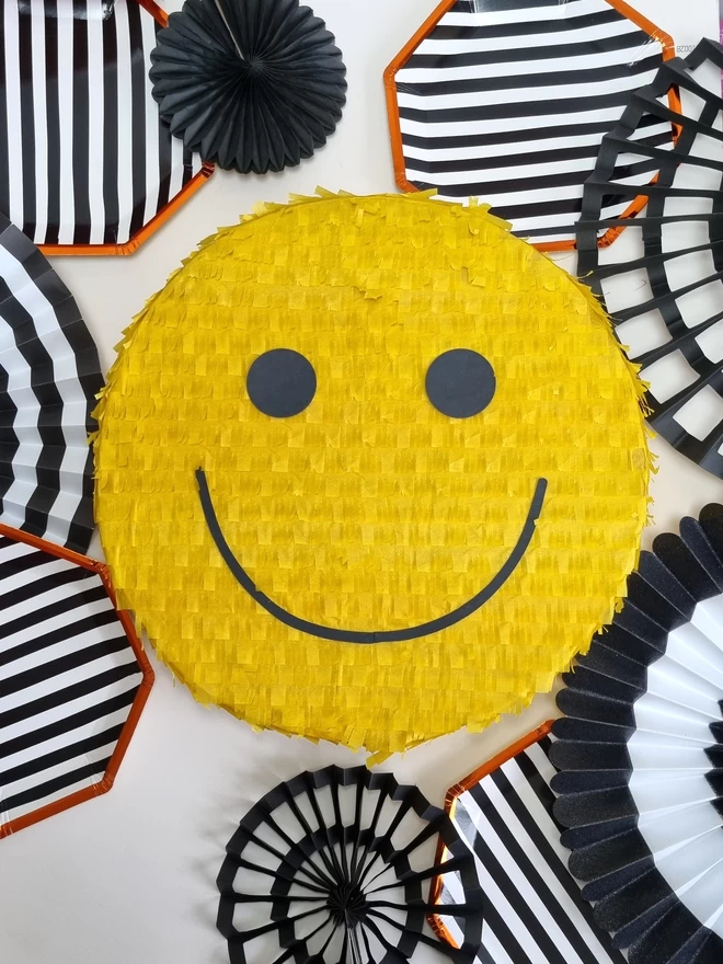 Happy Smiley face pinata in yellow on a black and white background