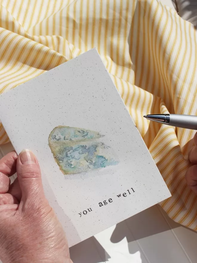 'You Age Well' Card being held with pen in other hand