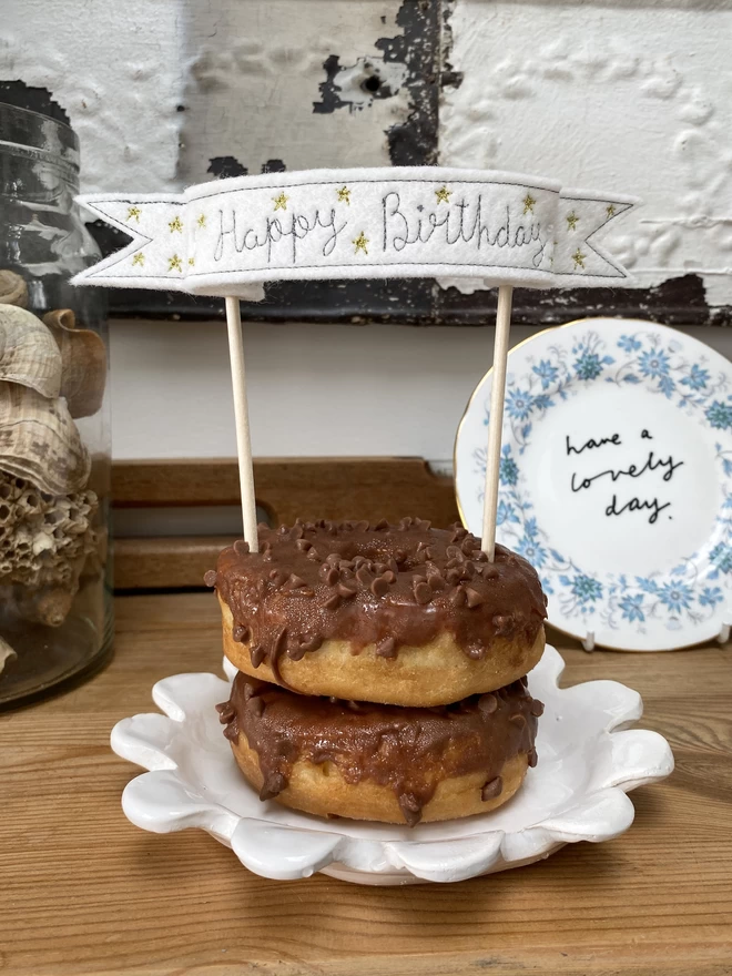 Star Banner Cake Topper in chocolate doughnut on shelf with plate in background