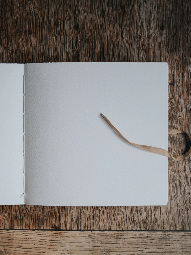 Open pages of journal made with watercolour paper with a gold ribbon tie
