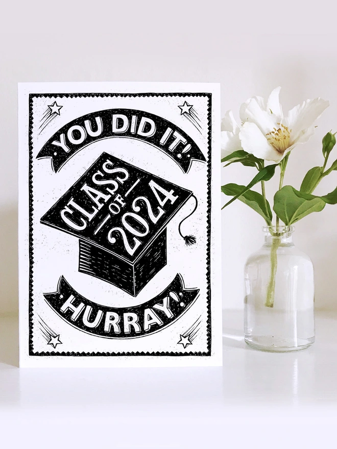 black and white class of 2024 graduation card with vase of white flowers