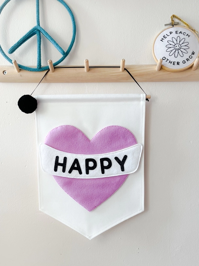 White fabric banner with a lilac heart saying the word happy