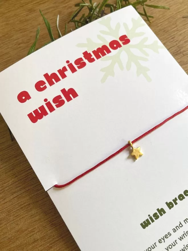 A christmas wish bracelet in red with a gold star charm.