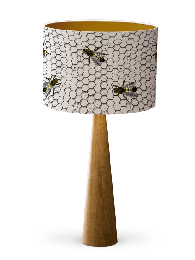 Drum Lampshade featuring honey bees on a honeycomb with a gold inner on a wooden base on a white background