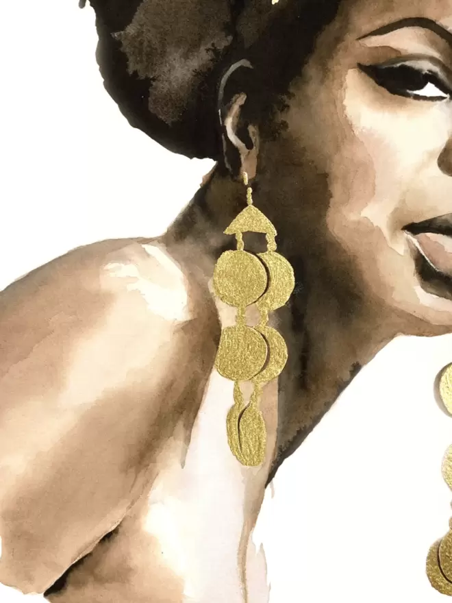 This is a detail shot showing the gold leaf earrings dangling from her ears and you can see one of her eyes, heightened and lengthened with Sixties style black eyeliner.