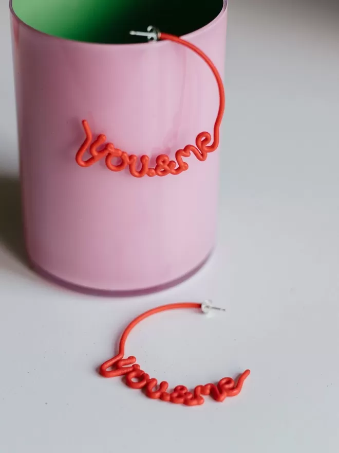 You & Me hoops by Zoe Sherwood large in red seen in a pink cup.