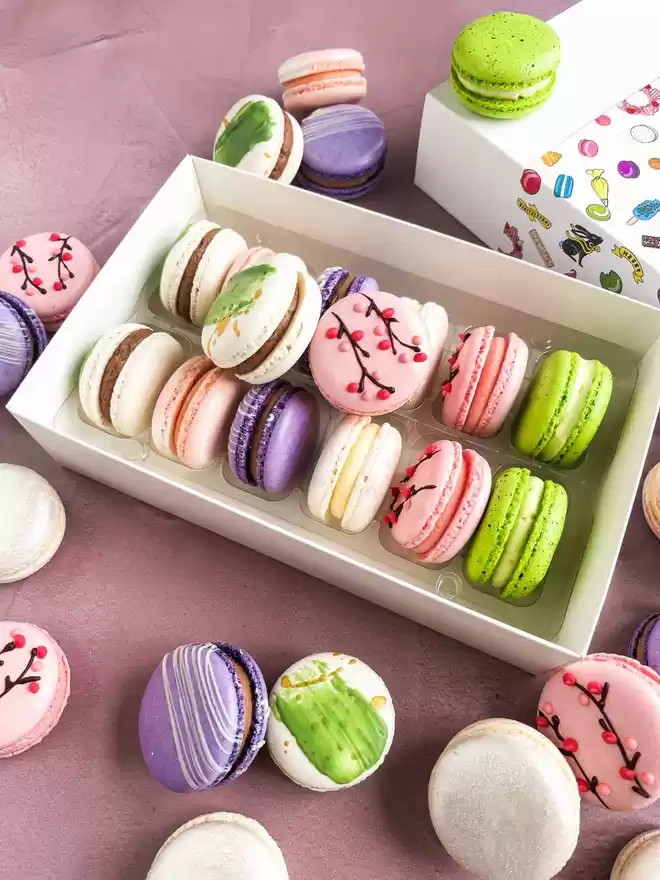 an assortment of colourful spring themed macarons in a white gift box
