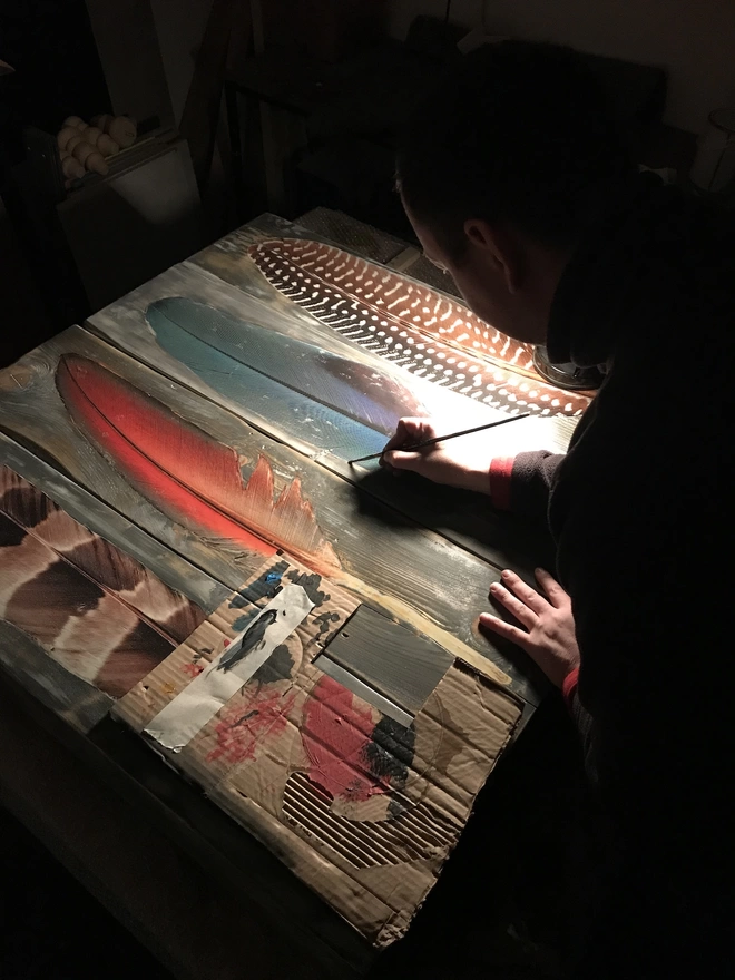 a man painting in the feather artwork in a workshop